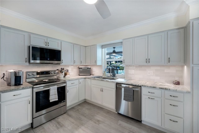 kitchen with sink, light wood-type flooring, ceiling fan, stainless steel appliances, and backsplash