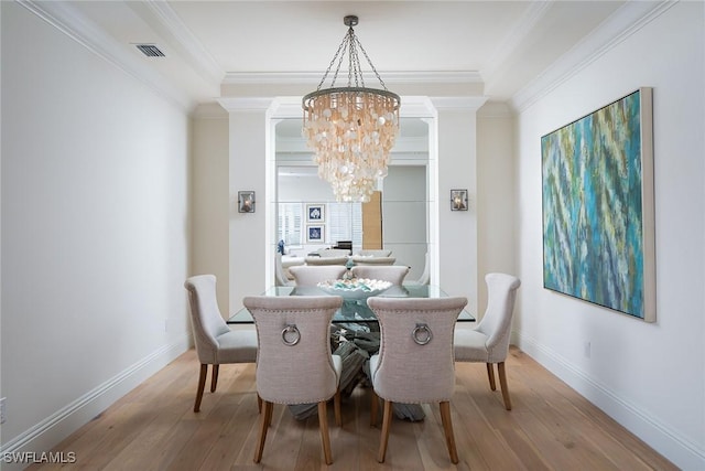 dining room with an inviting chandelier, crown molding, and hardwood / wood-style flooring