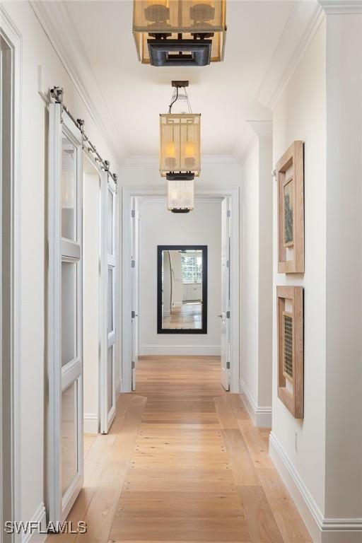 hallway with crown molding, a barn door, and light wood-type flooring