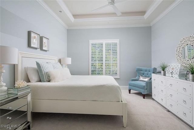 carpeted bedroom with crown molding, a tray ceiling, and ceiling fan