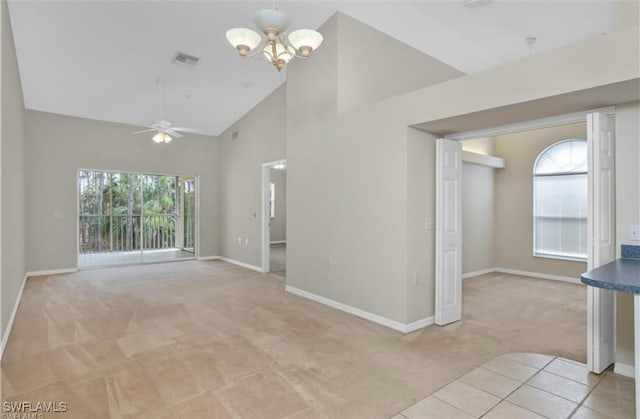 spare room with ceiling fan with notable chandelier, light colored carpet, and high vaulted ceiling