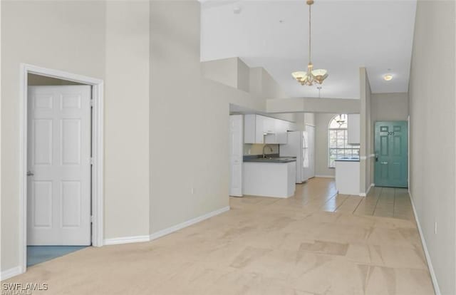 unfurnished living room with sink, light colored carpet, a chandelier, and a high ceiling