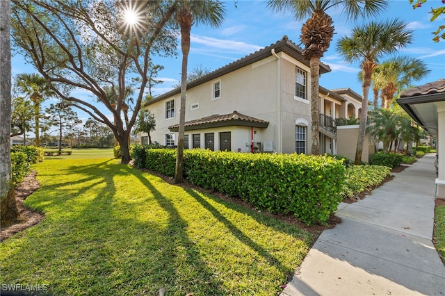 view of side of property with a tile roof, a lawn, and stucco siding