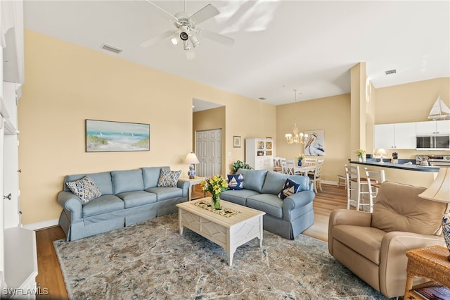 living room with ceiling fan with notable chandelier and hardwood / wood-style floors