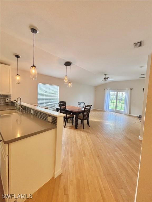 kitchen featuring sink, white cabinetry, decorative light fixtures, ceiling fan, and light hardwood / wood-style floors