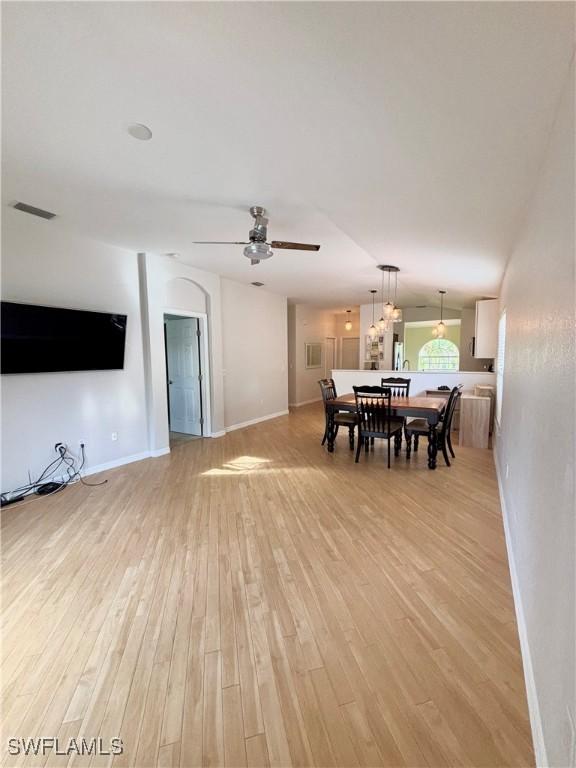 dining area with ceiling fan, lofted ceiling, and light wood-type flooring