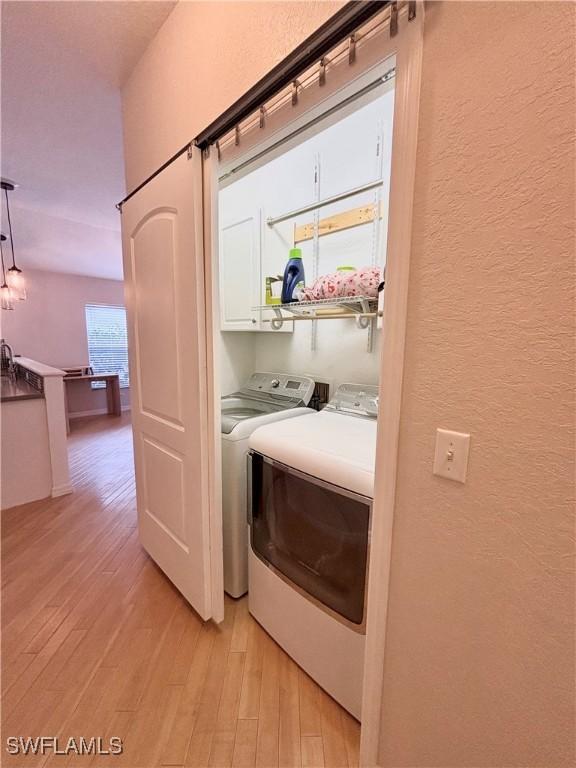 laundry area with washer and clothes dryer and light hardwood / wood-style flooring