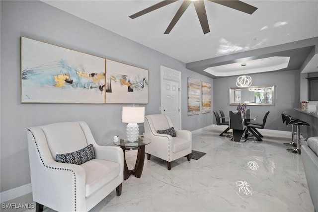 living area featuring ceiling fan and a tray ceiling