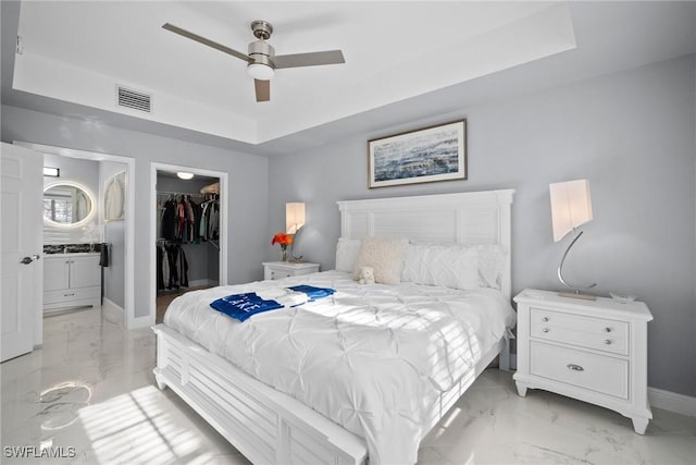 bedroom with a tray ceiling, a closet, ceiling fan, and a spacious closet