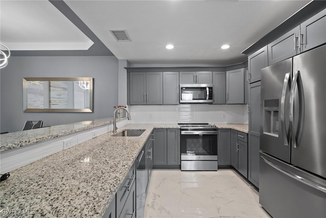 kitchen with stainless steel appliances, sink, backsplash, and light stone counters