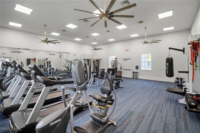 gym with dark colored carpet, ceiling fan, and a towering ceiling