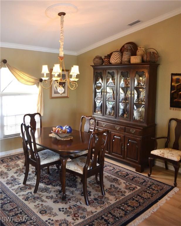 dining area featuring crown molding, a chandelier, and light hardwood / wood-style flooring