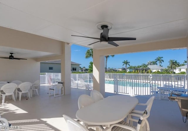 view of patio with a ceiling fan, outdoor dining area, fence, and a community pool