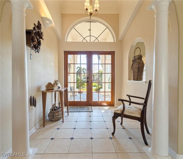 entryway featuring french doors, ornate columns, a chandelier, light tile patterned floors, and ornamental molding