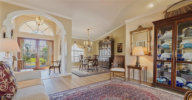 sitting room featuring french doors, ornate columns, crown molding, wood-type flooring, and a notable chandelier