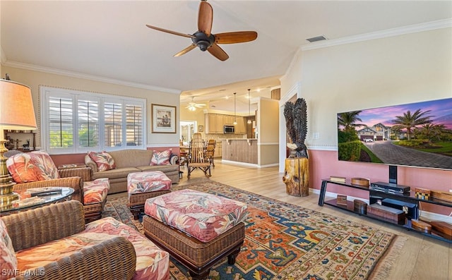 living area featuring ceiling fan, light wood-style floors, visible vents, and crown molding