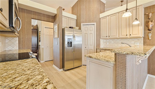 kitchen with a peninsula, appliances with stainless steel finishes, light stone countertops, light wood finished floors, and decorative light fixtures