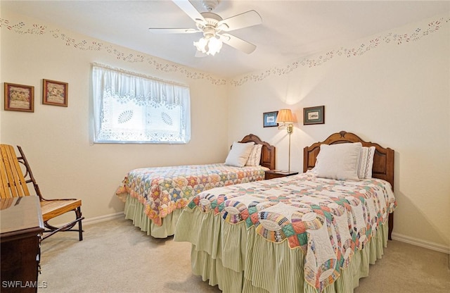 bedroom featuring light carpet, a ceiling fan, and baseboards