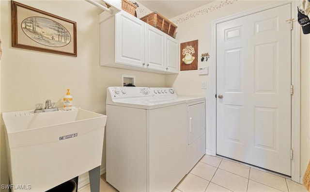 clothes washing area featuring cabinets, sink, washing machine and dryer, and light tile patterned floors