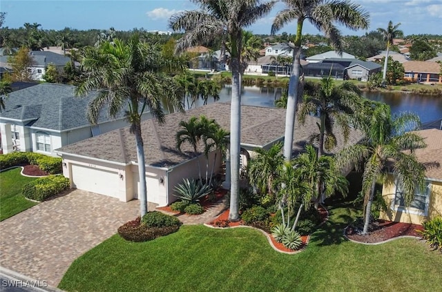 view of front of house featuring a garage, a residential view, decorative driveway, and a water view