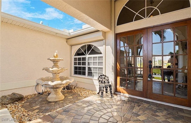 view of exterior entry featuring french doors and stucco siding