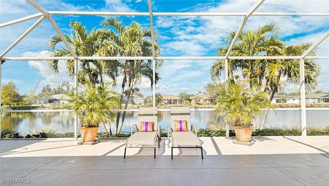 view of patio with a water view and glass enclosure