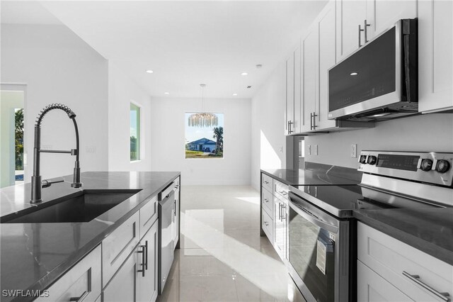 kitchen featuring pendant lighting, stainless steel appliances, sink, and white cabinets