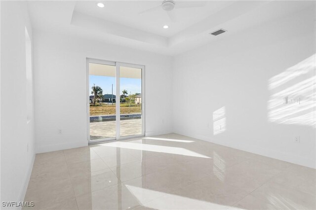 unfurnished room with light tile patterned floors, a tray ceiling, and ceiling fan