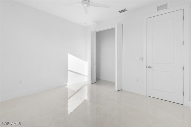 tiled empty room featuring ceiling fan