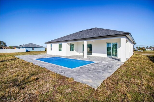 rear view of property featuring a fenced in pool, a patio area, and a lawn