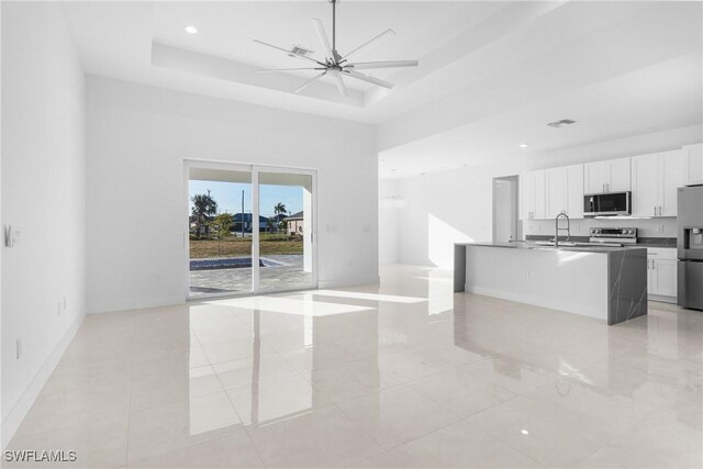 kitchen featuring appliances with stainless steel finishes, white cabinets, ceiling fan, and a tray ceiling