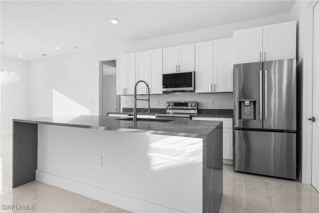 kitchen with sink, stainless steel appliances, white cabinets, a center island with sink, and decorative light fixtures