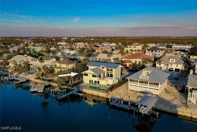 aerial view at dusk with a water view and a residential view