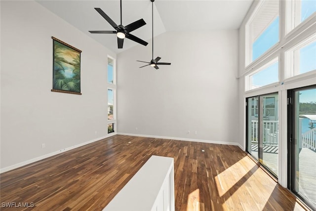 unfurnished living room featuring baseboards, a ceiling fan, wood finished floors, and high vaulted ceiling