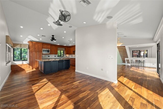 kitchen featuring lofted ceiling, sink, stainless steel microwave, dark hardwood / wood-style flooring, and a kitchen island