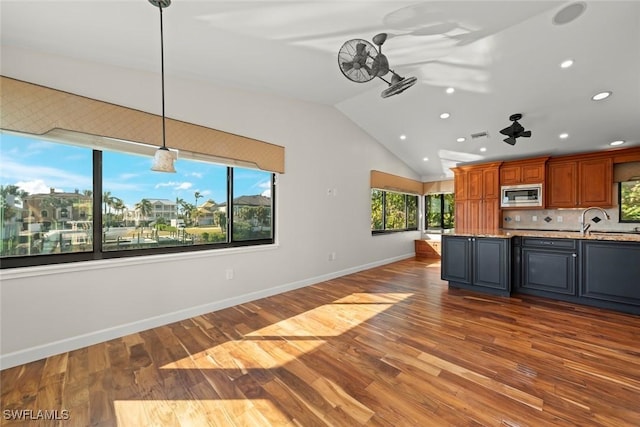 kitchen featuring recessed lighting, stainless steel microwave, a wealth of natural light, and lofted ceiling