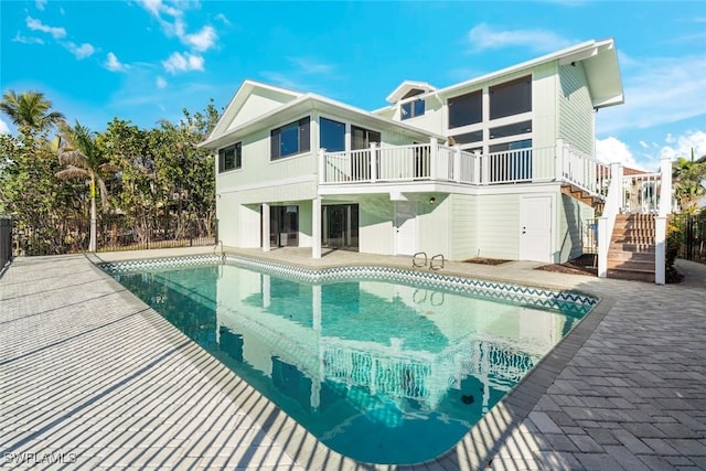 rear view of house with stairs, a balcony, a fenced in pool, and a patio
