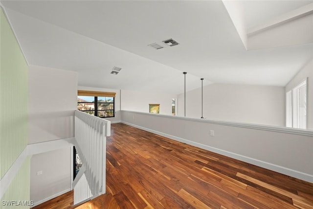 unfurnished room with baseboards, visible vents, wood finished floors, and lofted ceiling