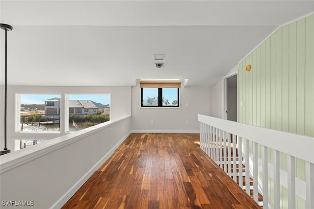 hall with hardwood / wood-style flooring, vaulted ceiling, and a water view