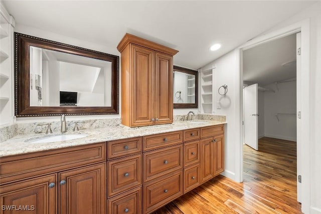 bathroom featuring double vanity, baseboards, a sink, and wood finished floors