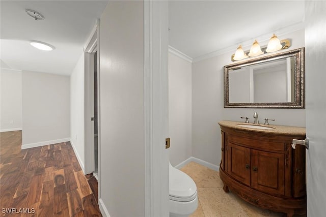 bathroom featuring vanity, hardwood / wood-style flooring, ornamental molding, and toilet