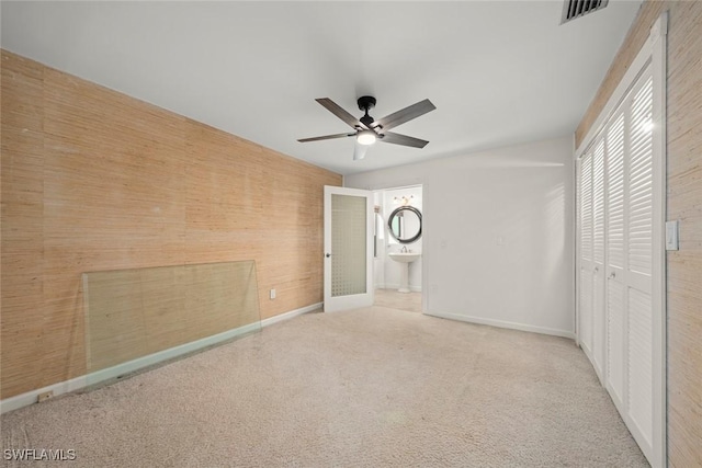 unfurnished bedroom featuring connected bathroom, sink, ceiling fan, light carpet, and a closet