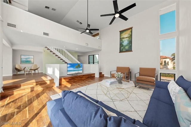 living room featuring visible vents, a towering ceiling, and stairway
