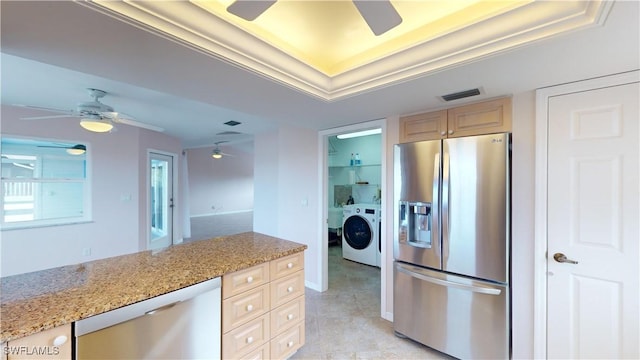 kitchen with light stone countertops, washer / dryer, stainless steel appliances, and light brown cabinets