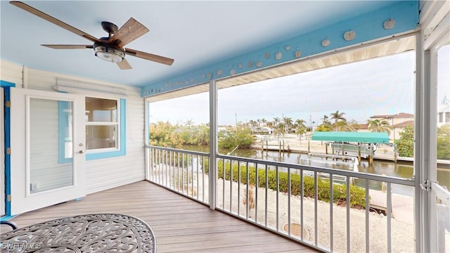 sunroom with ceiling fan and a water view