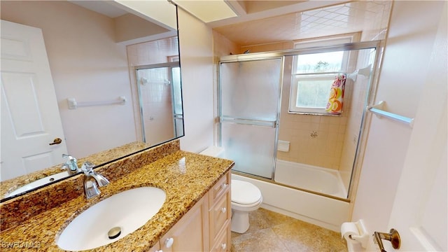 full bathroom with enclosed tub / shower combo, vanity, and toilet