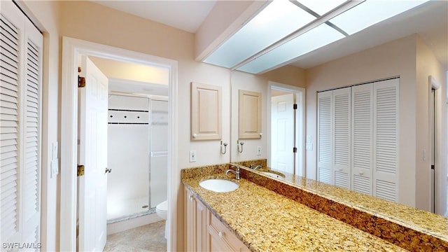 bathroom with vanity, a shower with shower door, and toilet