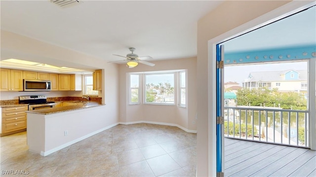 kitchen featuring stainless steel appliances, light stone countertops, kitchen peninsula, and light brown cabinets