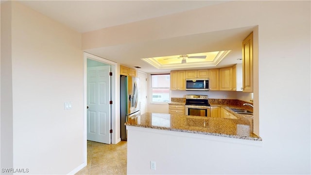 kitchen featuring sink, light brown cabinets, appliances with stainless steel finishes, a raised ceiling, and kitchen peninsula