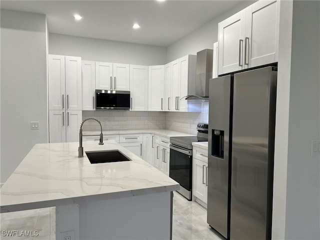 kitchen with sink, wall chimney range hood, stainless steel appliances, and a center island with sink